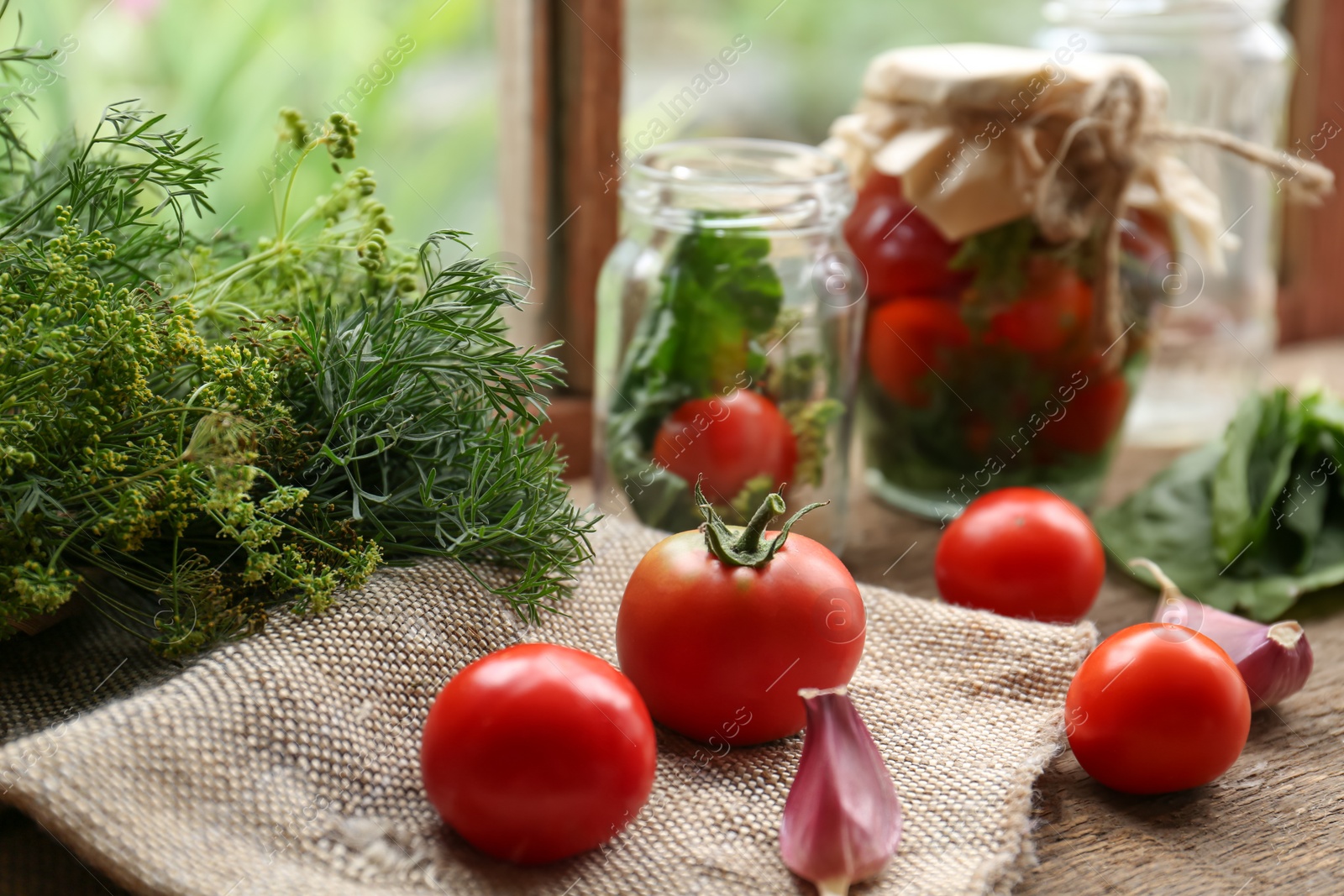 Photo of Glass jars, fresh vegetables and herbs on wooden table indoors. Pickling recipe