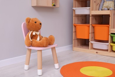 Photo of Teddy bear on chair in child`s playroom. Cozy kindergarten interior