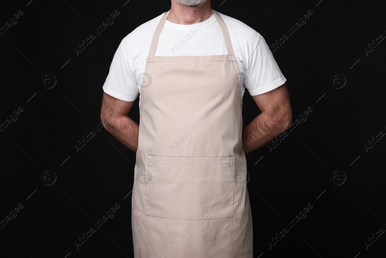 Photo of Man wearing kitchen apron on black background, closeup. Mockup for design