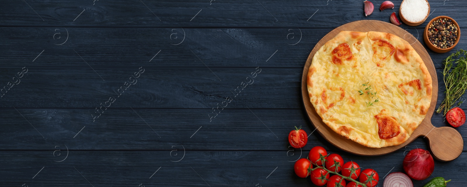 Image of Delicious Megrelian khachapuri served on dark blue wooden table, flat lay. Banner design with space for text