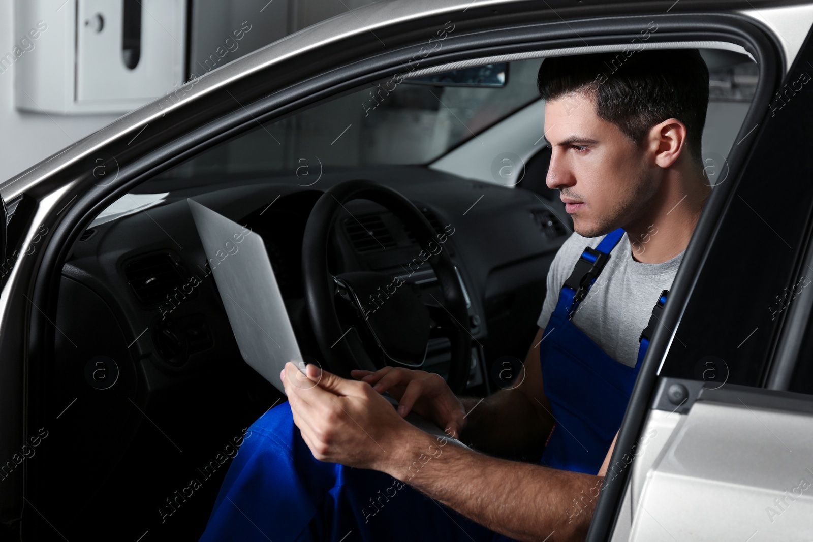 Photo of Mechanic with laptop doing car diagnostic at automobile repair shop