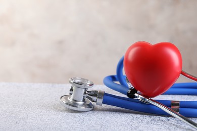 Stethoscope and red heart on grey stone table, closeup. Space for text