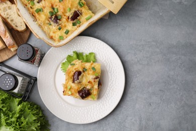 Photo of Tasty sausage casserole with green onions served on grey table, flat lay. Space for text