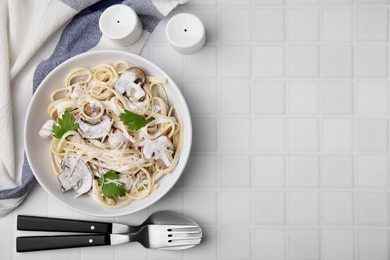 Delicious pasta with mushrooms served on white tiled table, flat lay. Space for text