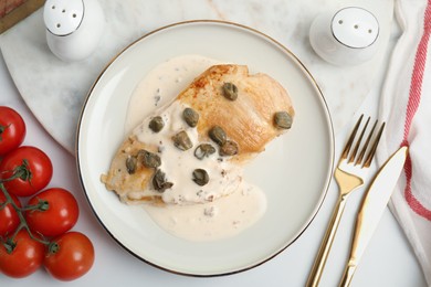 Photo of Delicious chicken fillet with capers and sauce served on white table, flat lay