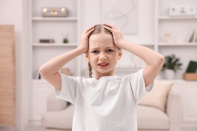 Photo of Little girl suffering from headache at home