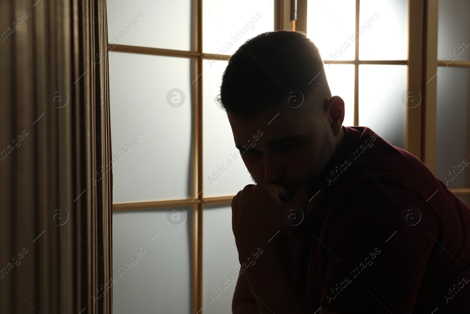 Photo of Silhouette of sad man at home. Space for text