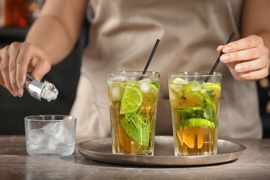 Photo of Bartender preparing delicious mint julep cocktail at table