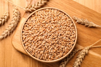Photo of Wheat grains with spikelets on wooden table, flat lay