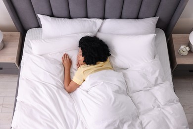 Photo of Beautiful young woman sleeping in soft bed at home, above view