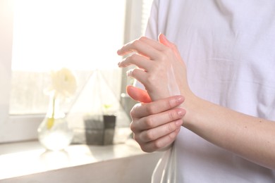 Woman applying hand cream at home, closeup