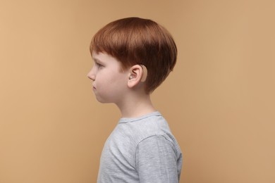 Photo of Little boy with hearing aid on pale brown background