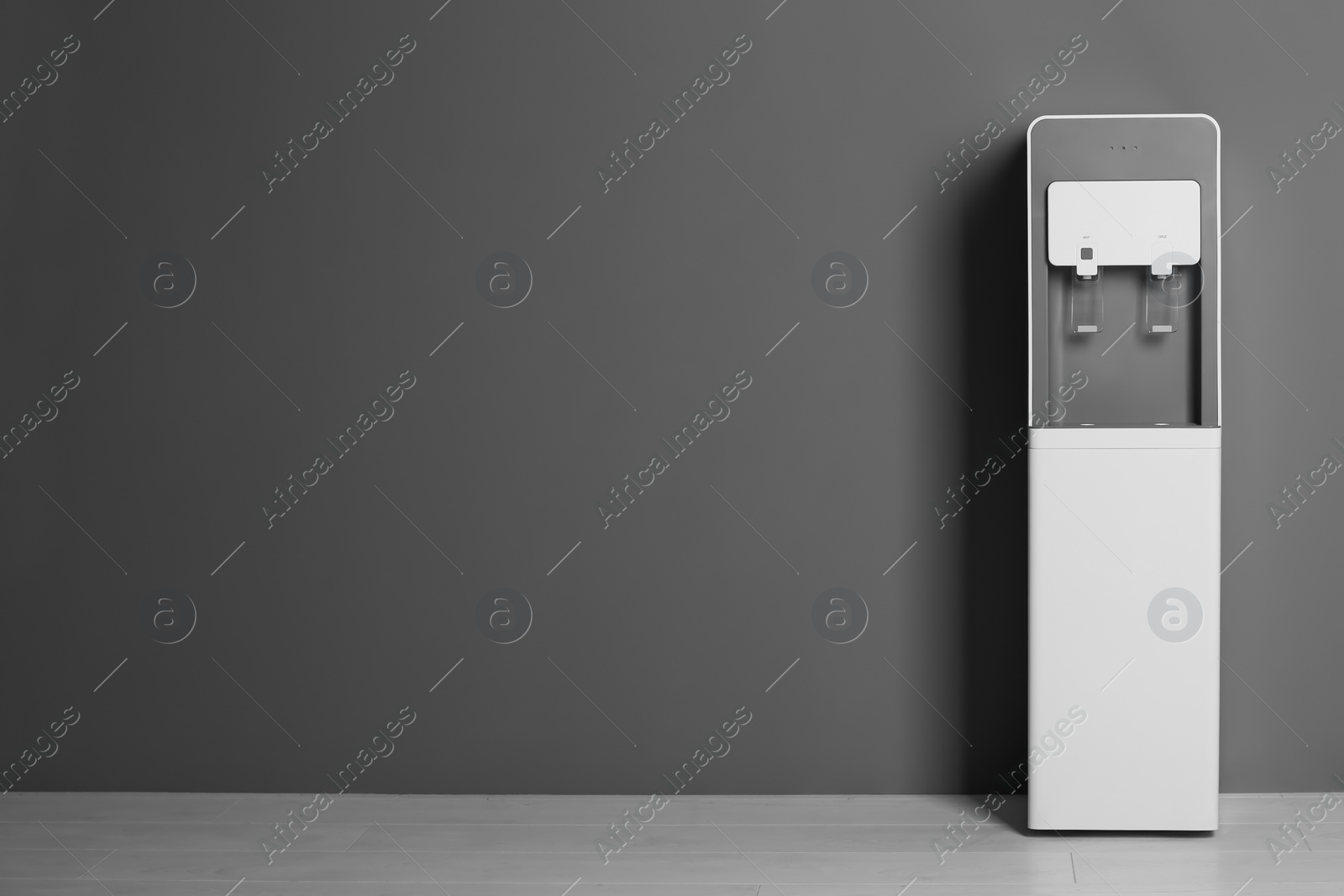 Photo of Modern water cooler against gray wall with space for text