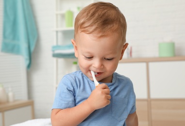 Cute little boy with toothbrush on blurred background