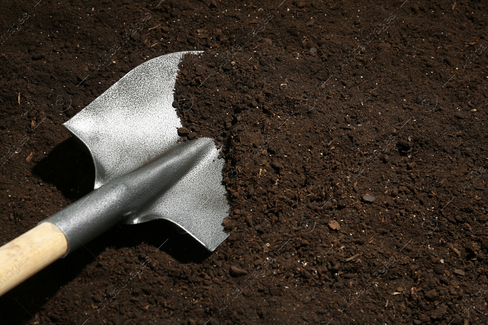 Metal shovel on fertile soil, space for text. Gardening tool Photo of Metal shovel on fertile soil, space for text. Gardening tool