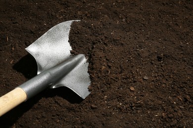 Photo of Metal shovel on fertile soil, space for text. Gardening tool
