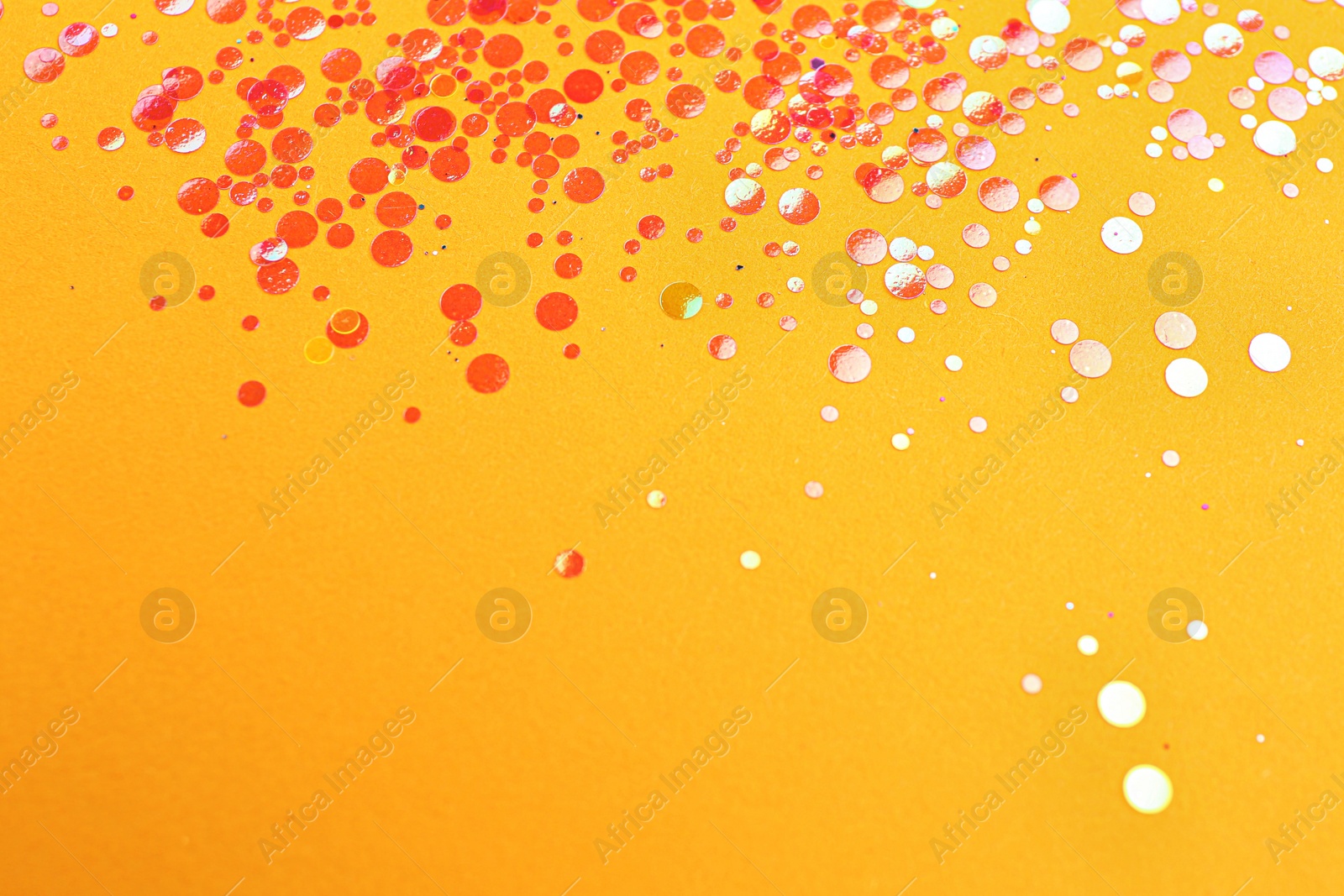 Photo of Shiny bright red glitter on pale orange background. Space for text