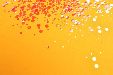 Photo of Shiny bright red glitter on pale orange background. Space for text