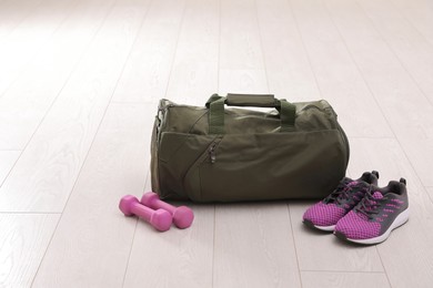 Photo of Sports bag and gym equipment on white floor