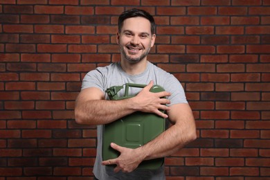 Man holding khaki metal canister against brick wall