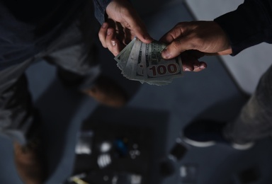 Addicted man buying drugs from dealer on blurred background, closeup