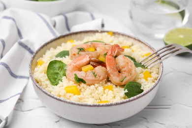Photo of Tasty couscous with shrimps, bell pepper and basil on white textured table, closeup