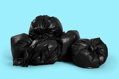 Photo of Trash bags full of garbage on light blue background