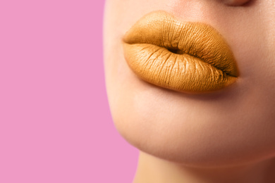 Image of Woman with golden lipstick on pink background, closeup