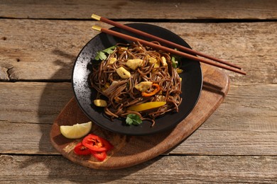 Photo of Stir-fry. Tasty noodles with vegetables and meat served on wooden table, above view