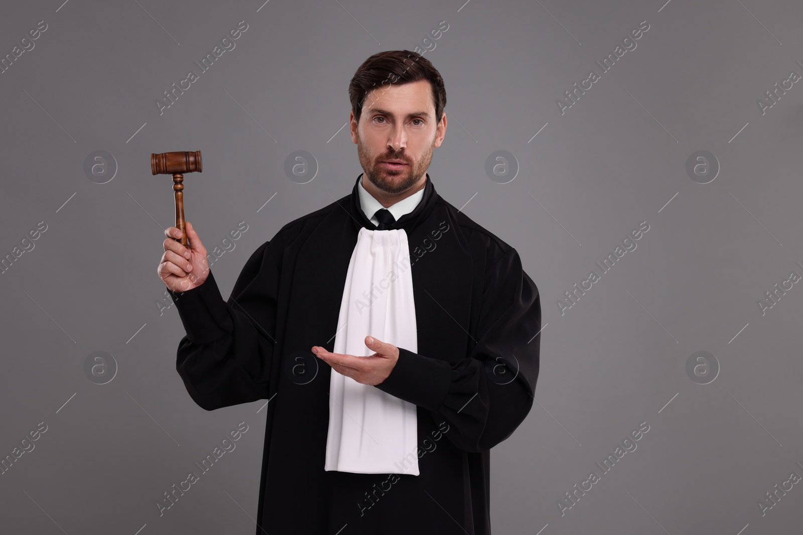 Photo of Portrait of judge showing gavel on grey background