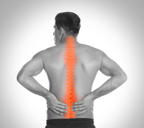 Man suffering from pain in spine on light background. Black and white effect