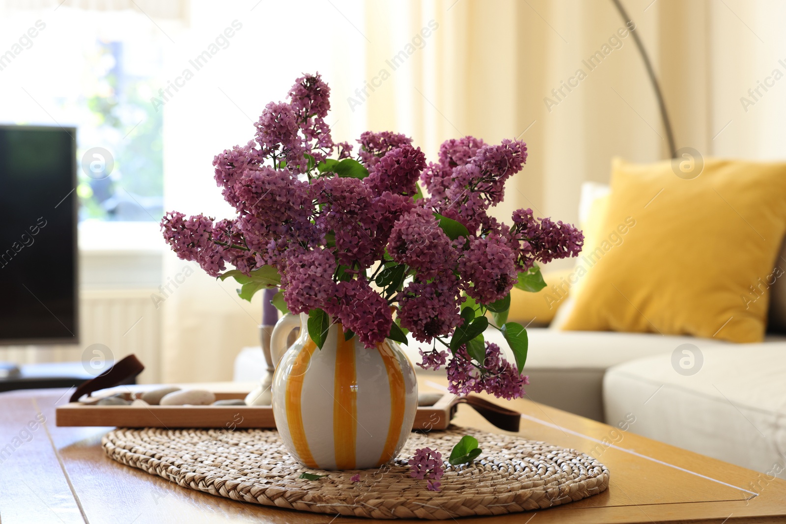 Photo of Beautiful fragrant lilac flowers in vase on table at home