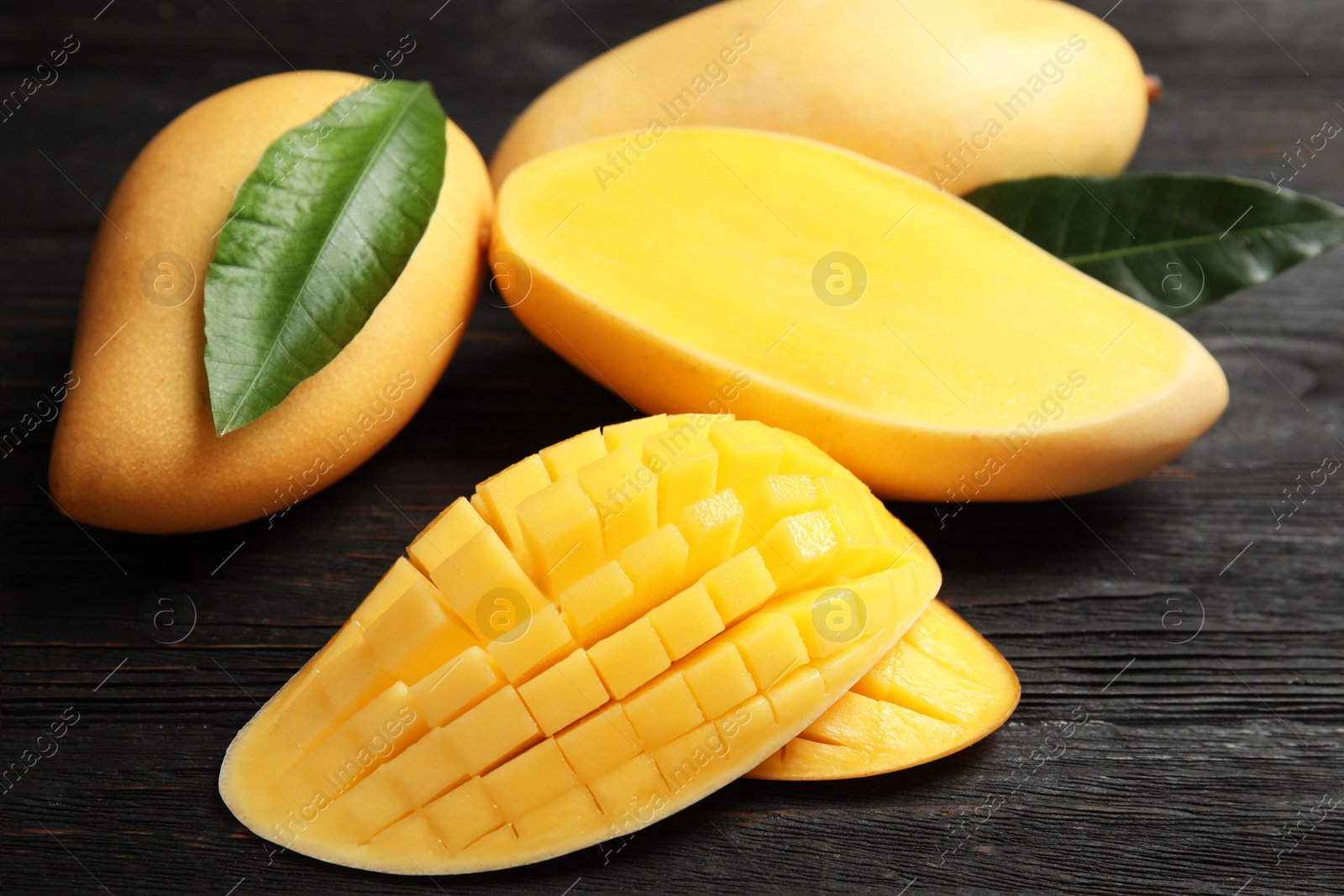 Photo of Ripe juicy mango on dark wooden table