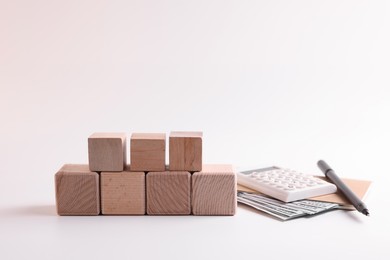 Photo of Word Tax, number 2024 made of wooden cubes, calculator, coins and banknotes on white background