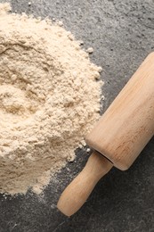 Photo of Pile of flour and rolling pin on grey textured table, top view