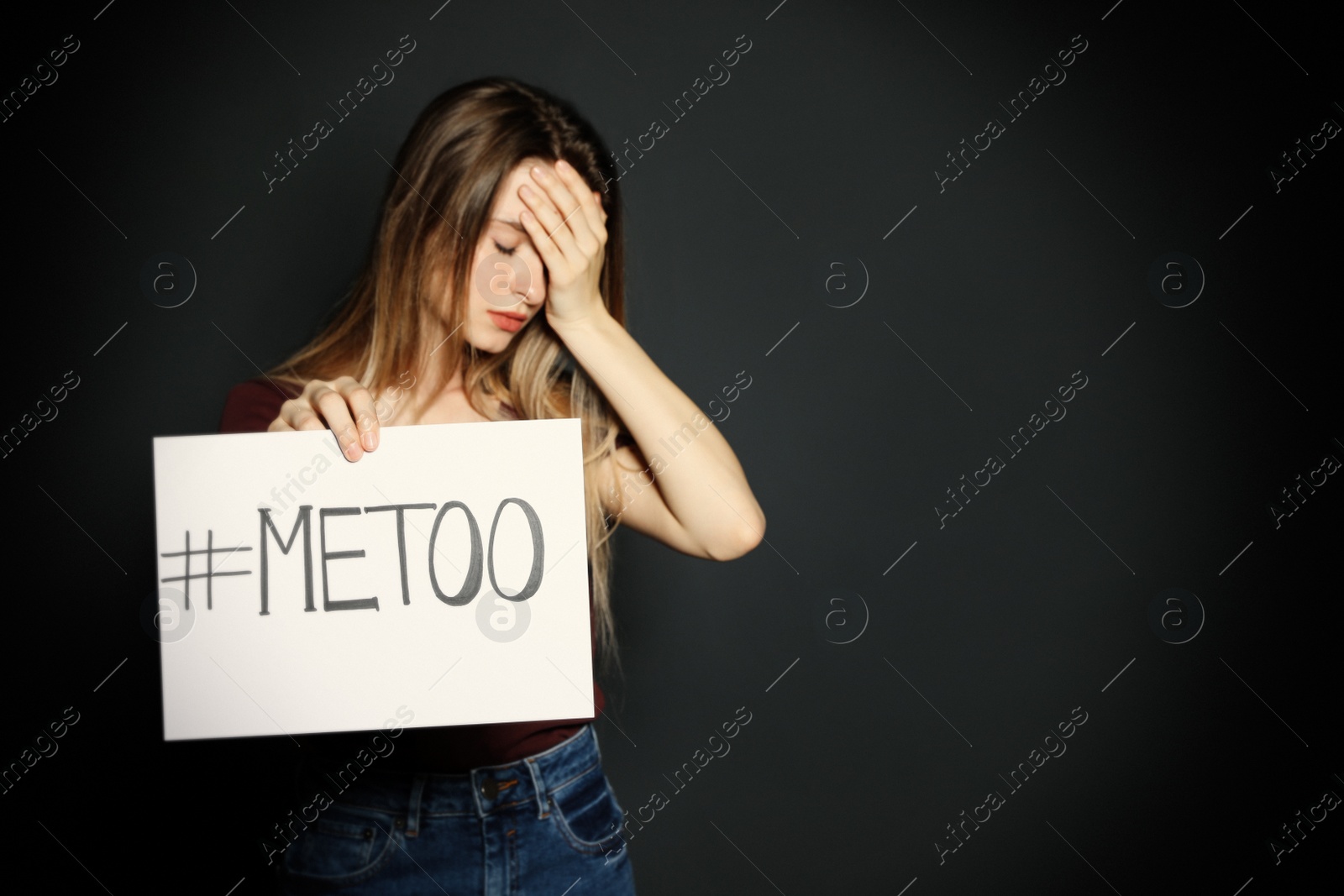 Photo of Young woman holding #METOO card against dark background. Space for text