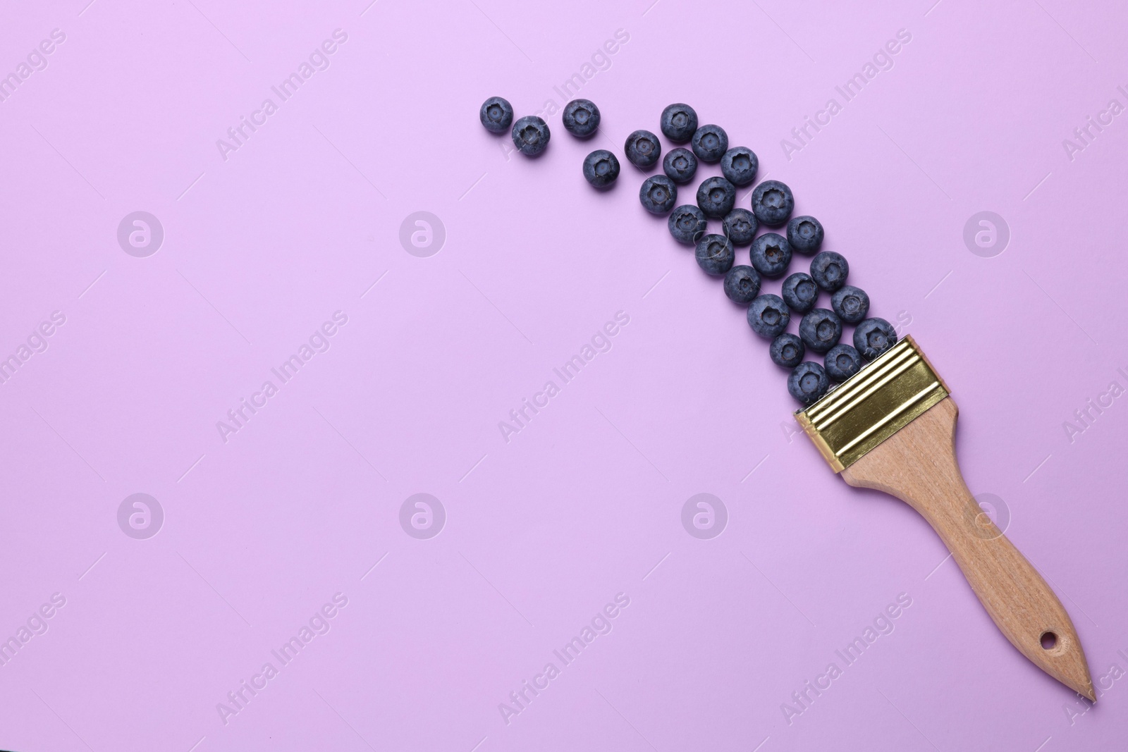 Photo of Creative flat lay composition with paint brush and blueberries on violet background. Space for text