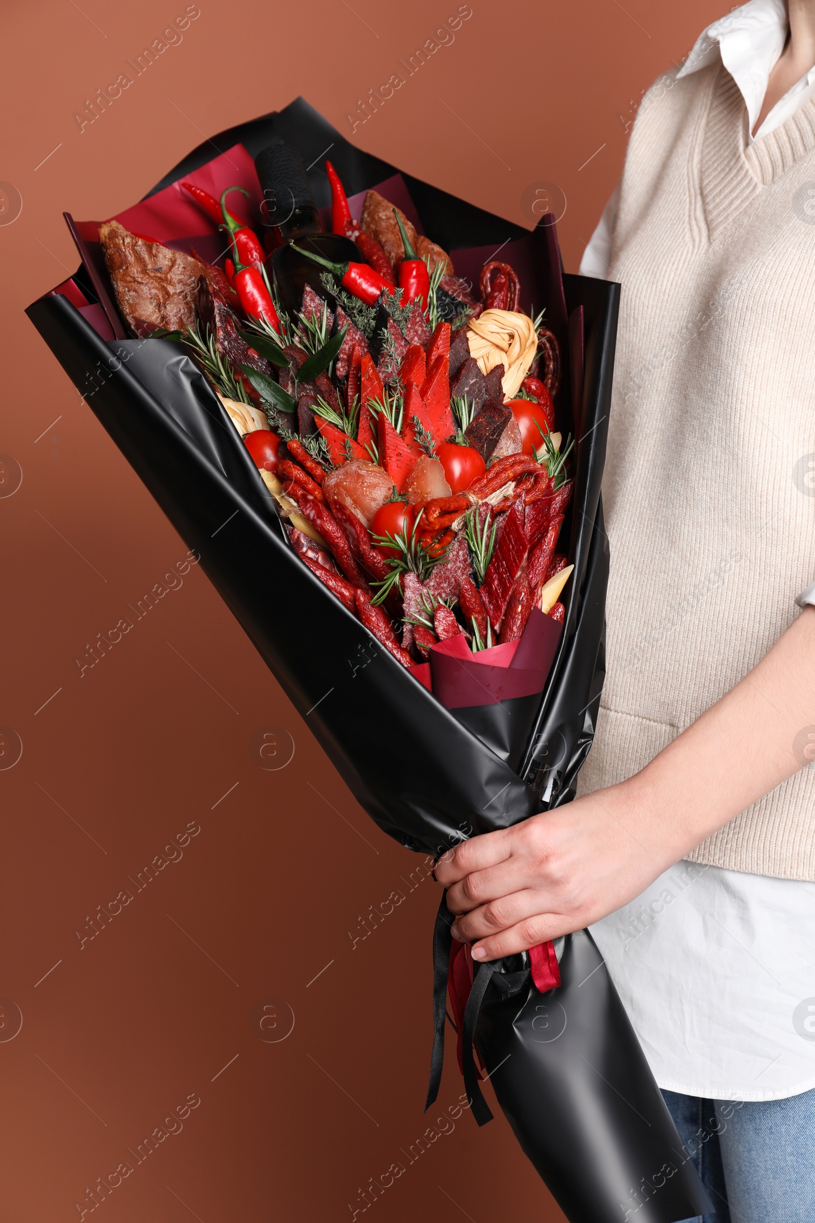 Photo of Woman with beautiful food bouquet on brown background, closeup