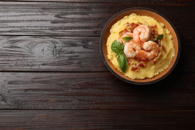 Fresh tasty shrimps, bacon, grits and basil in bowl on wooden table, top view. Space for text