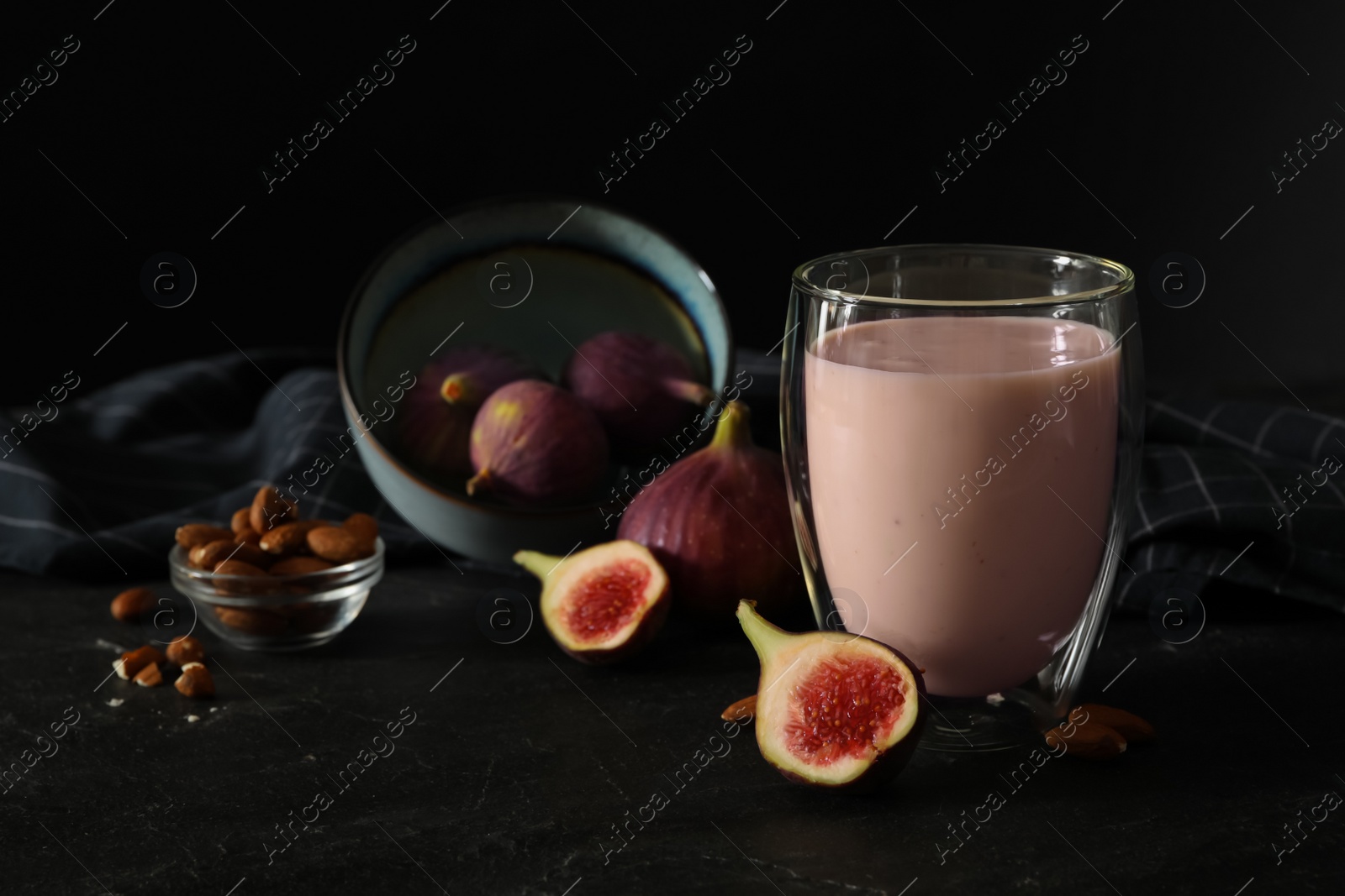 Photo of Delicious fig smoothie in glass on black table