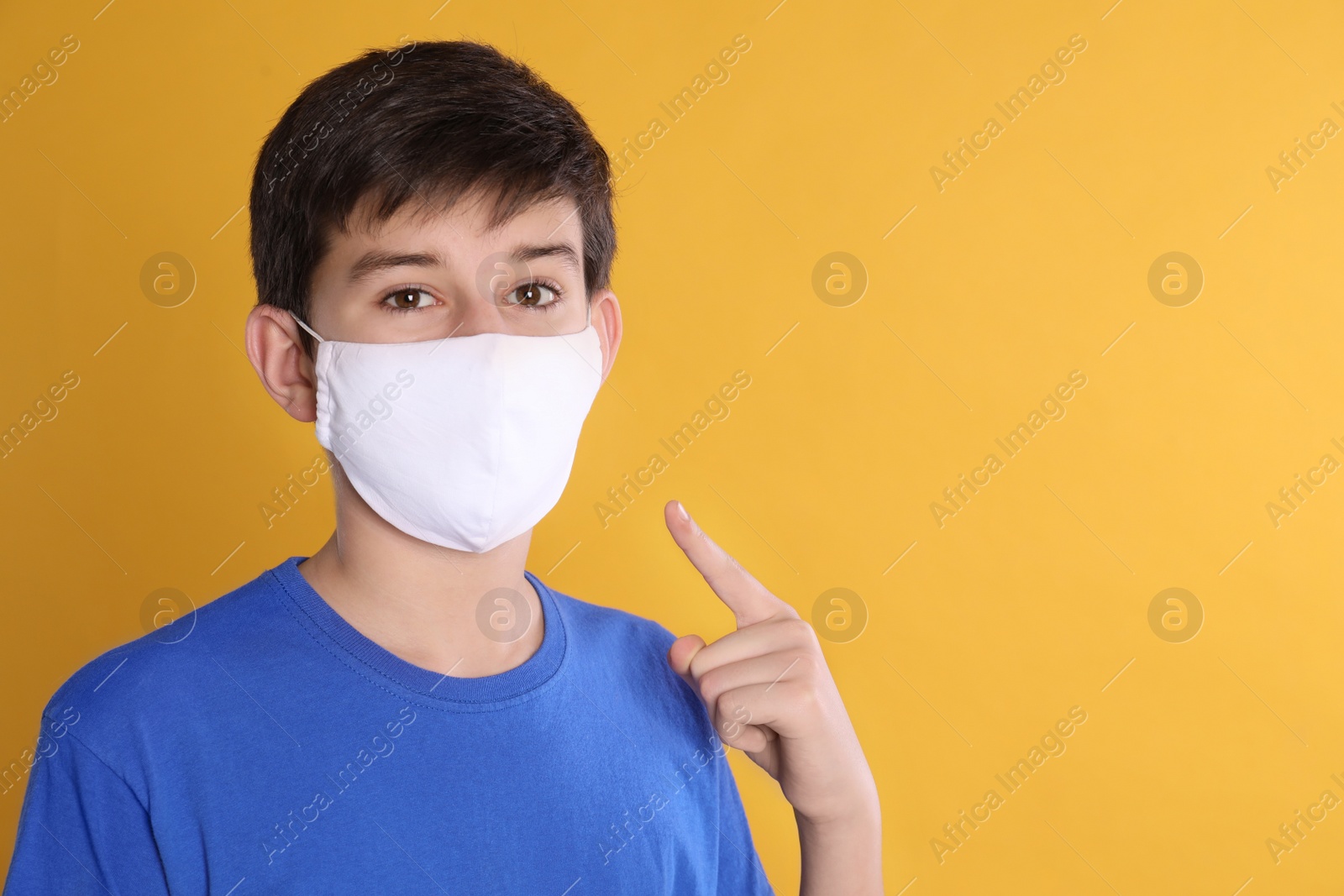 Photo of Boy wearing protective mask on yellow background, space for text. Child safety