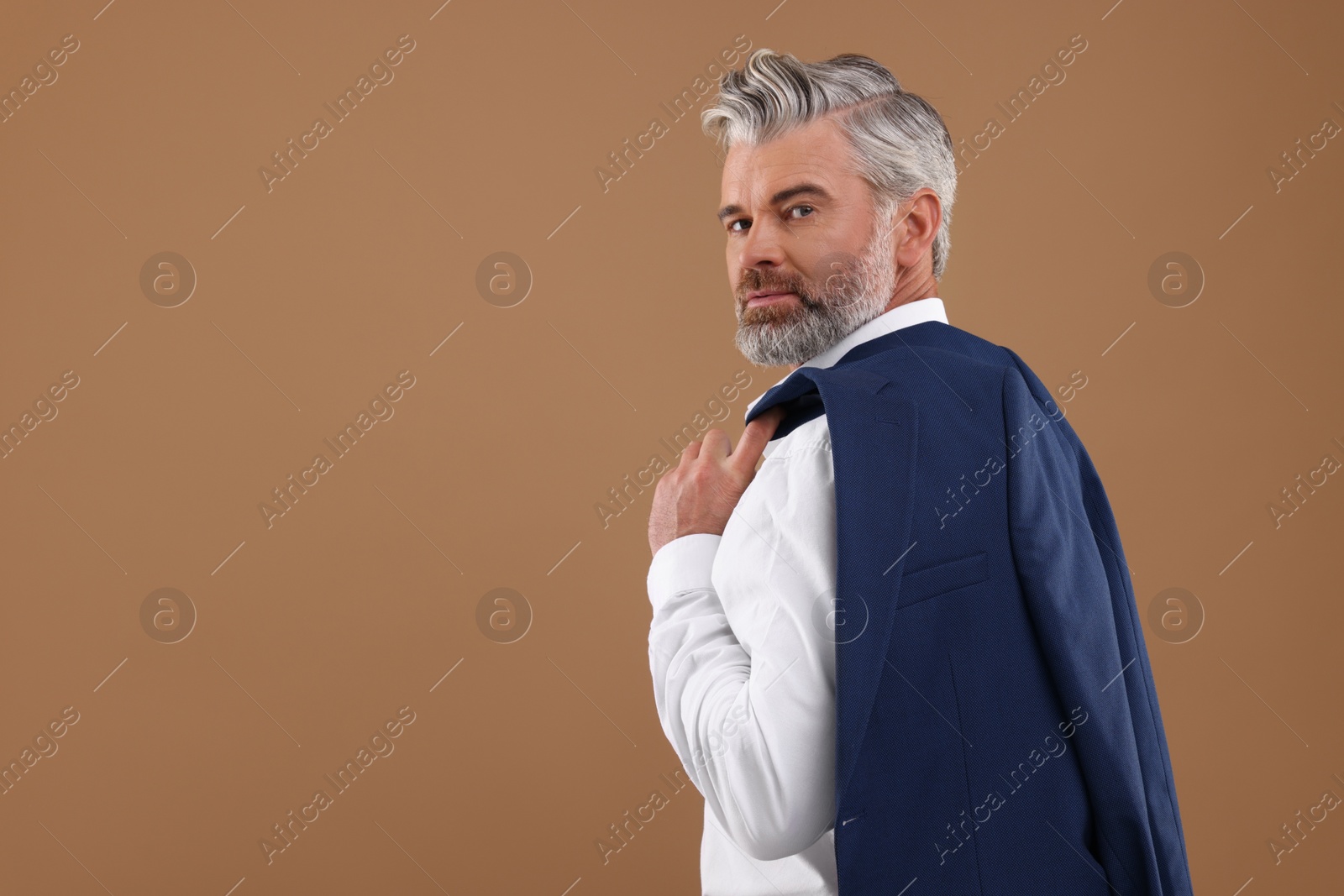 Photo of Portrait of confident man with beautiful hairstyle on light brown background. Space for text