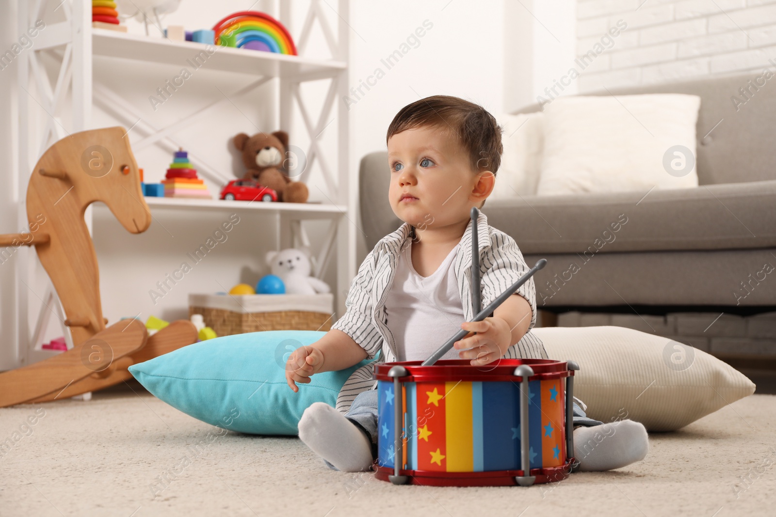 Photo of Cute little boy with toy drum and drumsticks at home