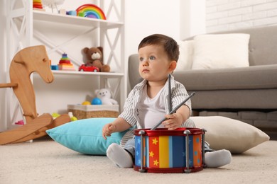 Photo of Cute little boy with toy drum and drumsticks at home