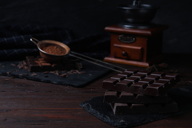 Photo of Tasty dark chocolate bars on wooden table