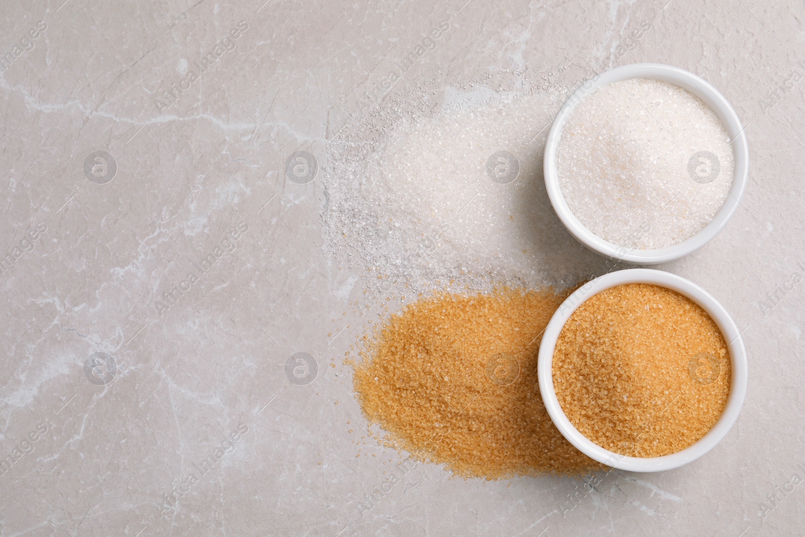 Photo of Bowls of white and brown sugar on light marble table, flat lay. Space for text