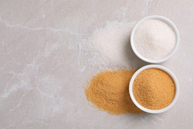 Bowls of white and brown sugar on light marble table, flat lay. Space for text