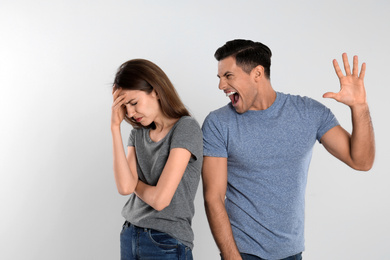 Photo of Man shouting at his girlfriend on light background. Relationship problems