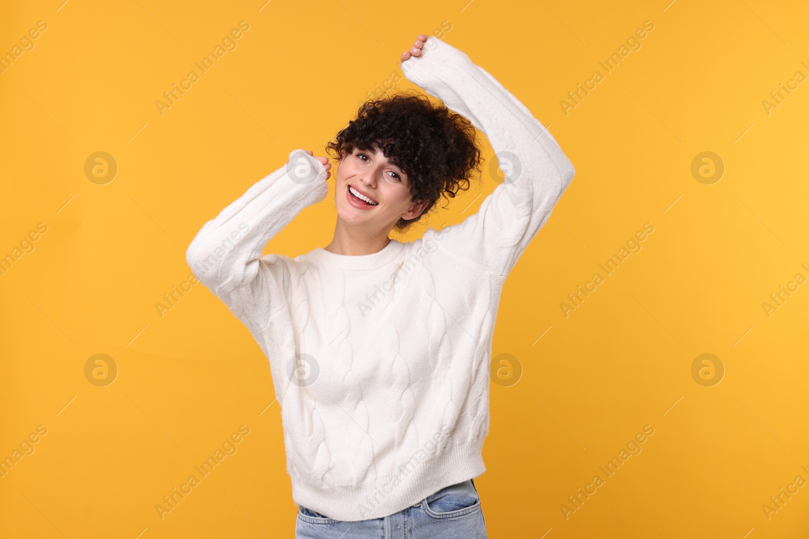 Photo of Happy young woman in stylish white sweater on yellow background