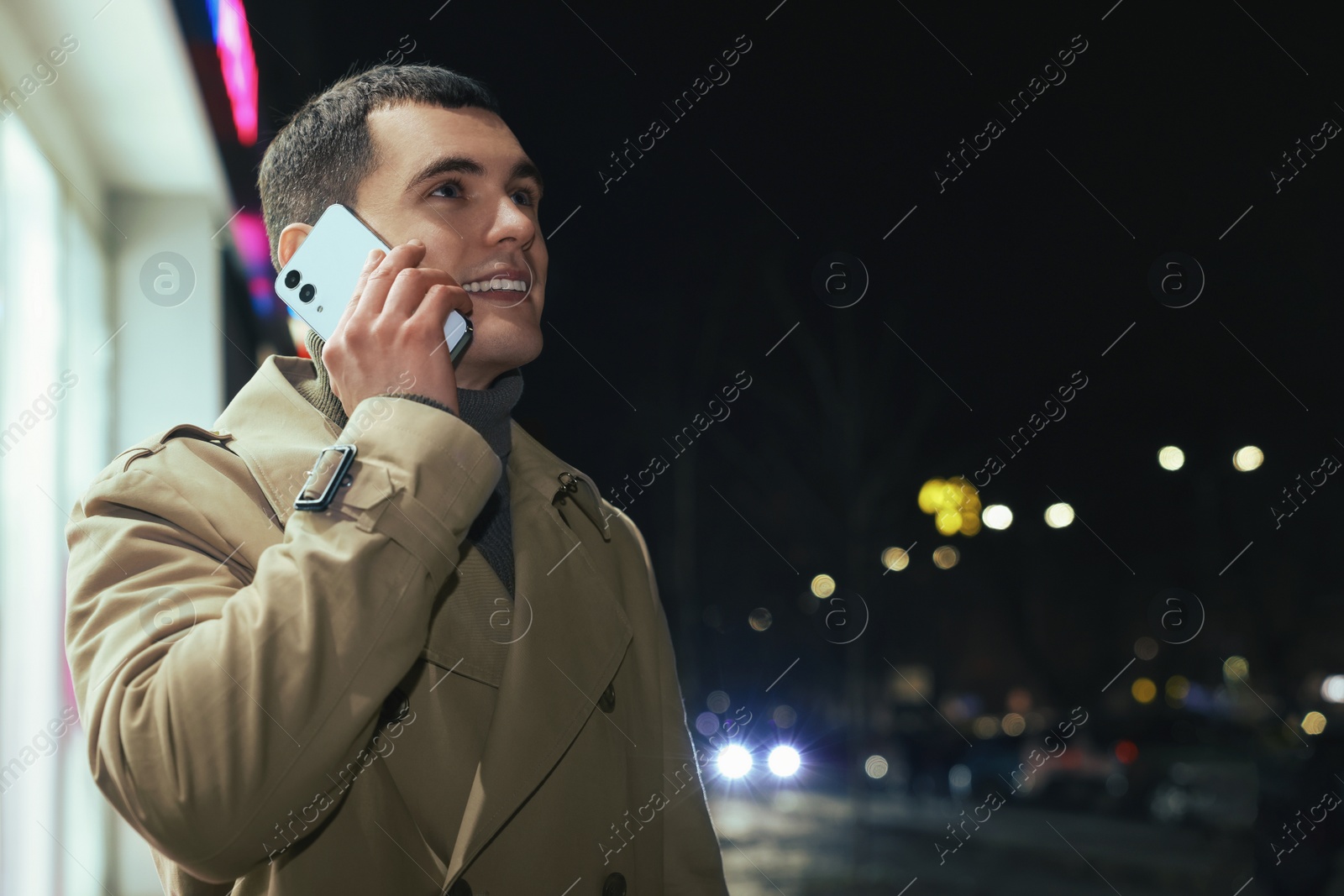 Photo of Man talking by smartphone on night city street, space for text